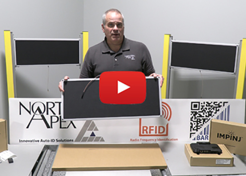 A Northern Apex employee holding an impinj reader with several other RFID antenna on a conveyor belt.